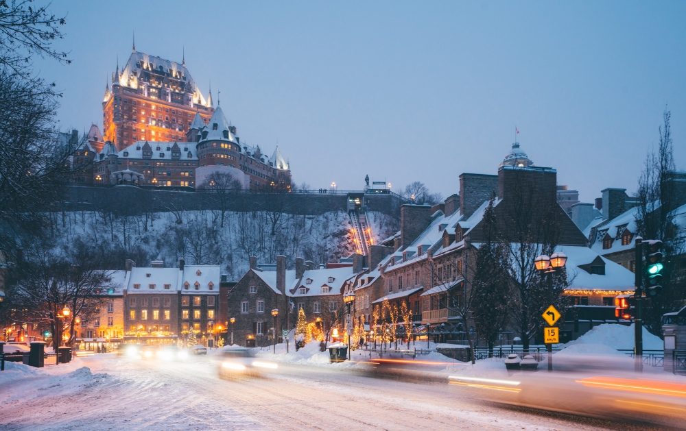 Quebec City Canada buildings in the winter with a car driving down the snowy road outside at night