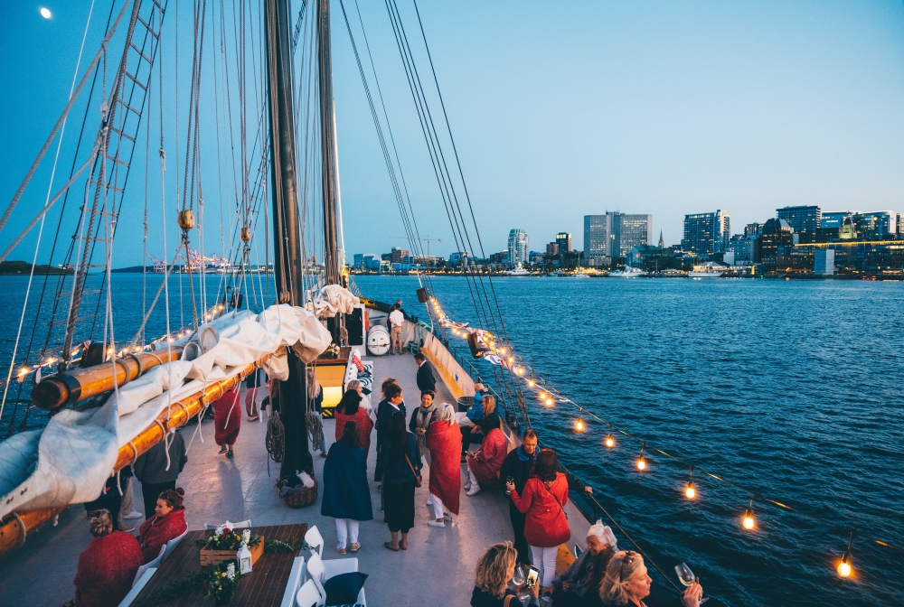 People on a boat at night in Halifax Nova Scotia Canada on the water with the view of the city and blue skies in the horizon